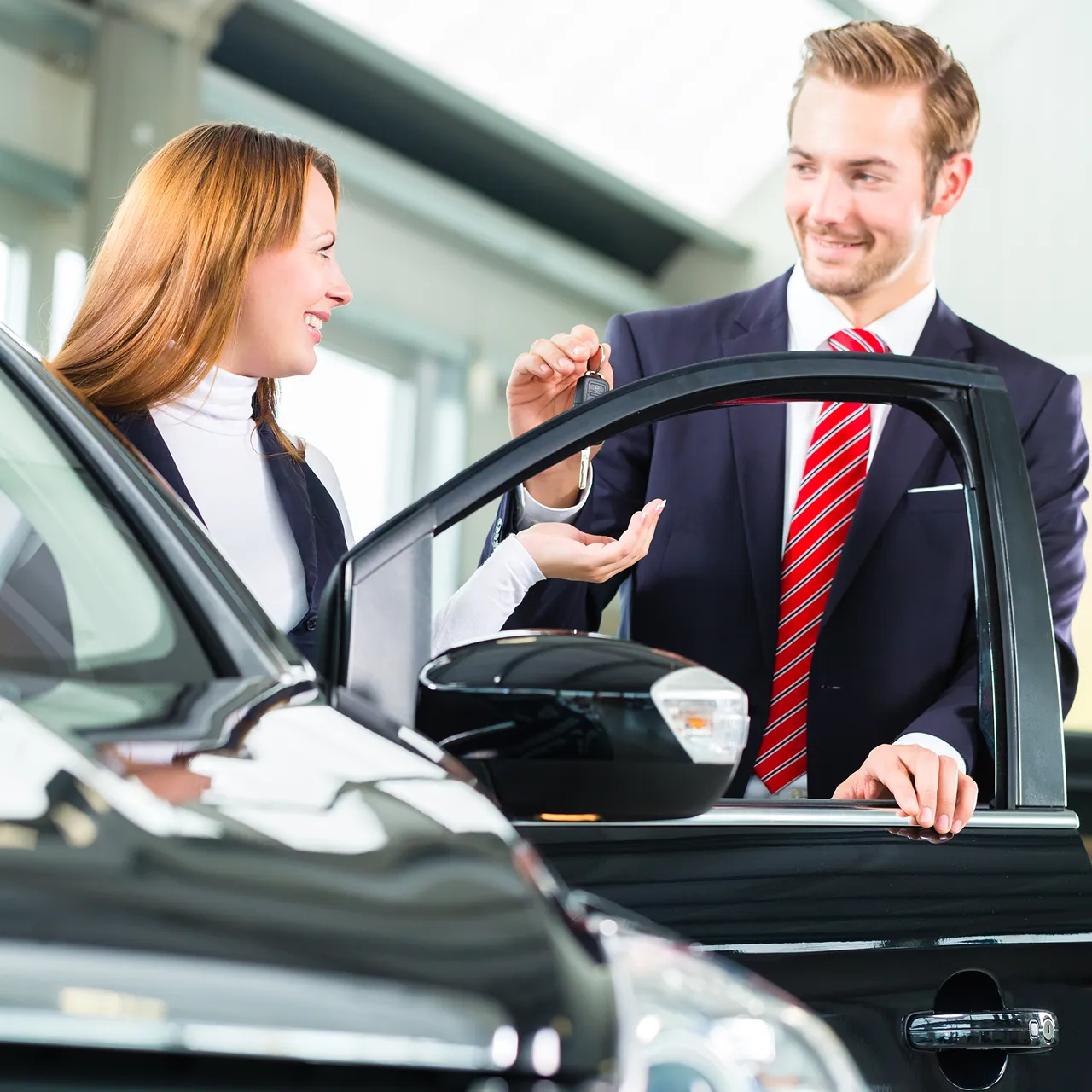 A smiling car rental customer receiving vehicle keys from an agent at our service desk.